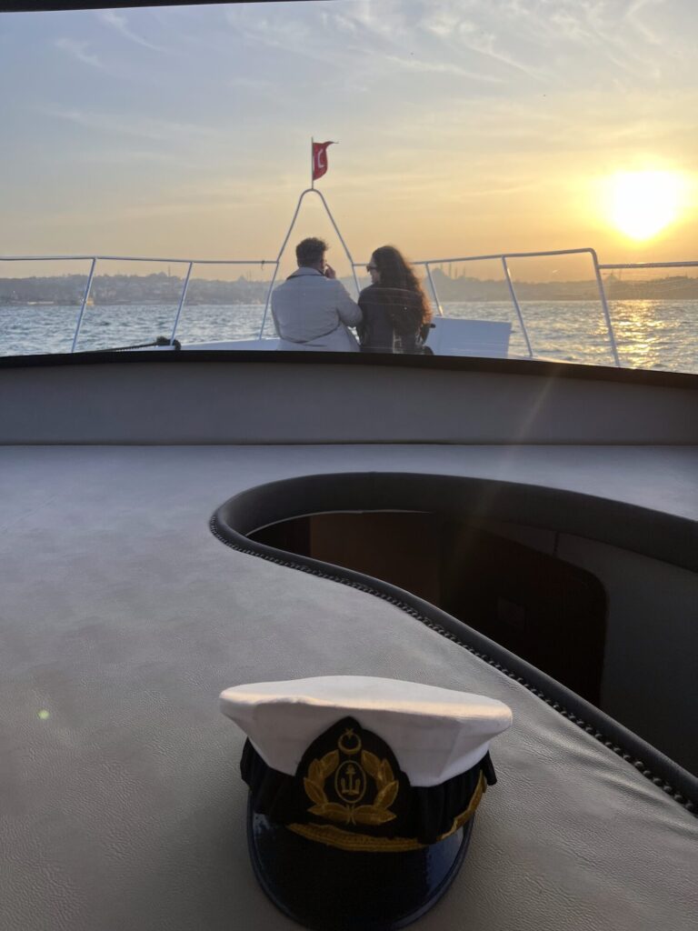 Kapitänsmütze auf dem Bugdeck einer privaten Yacht bei Sonnenuntergang, Istanbul