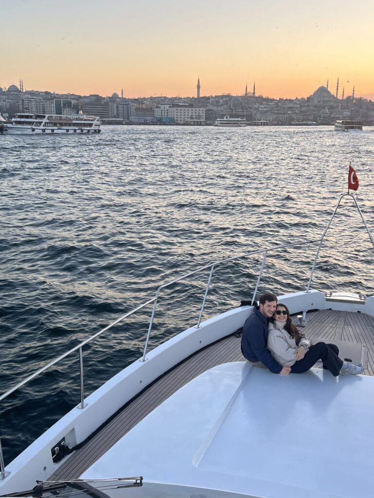Paar am Bug einer privaten Yacht mit der Istanbuler Skyline in der Abenddämmerung
