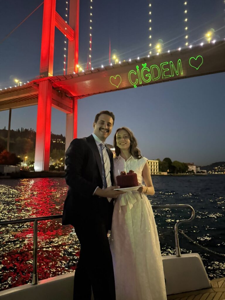 Paar mit Festtagstorte unter der beleuchteten Bosporus-Brücke