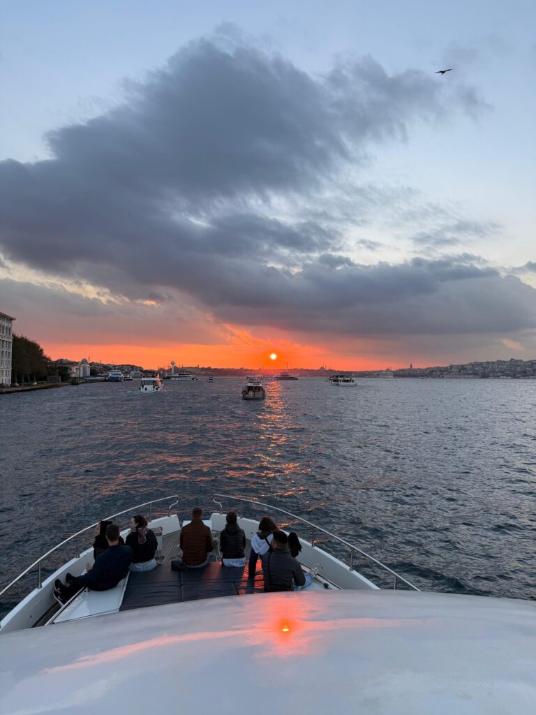 Gäste am Bug der Yacht unter einem feuerroten Sonnenuntergang in Istanbul