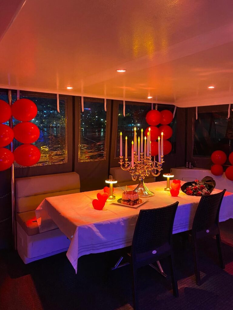 Romantisch gedeckter Tisch mit roten Ballons und Kerzenleuchter im Salon der Yacht