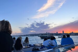 Guests watching the sunset from the deck on a shared Bosphorus group cruise in Istanbul
