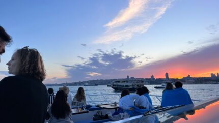 Guests watching the sunset from the deck on a shared Bosphorus group cruise in Istanbul