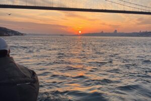 Sun setting under the Bosphorus Bridge, viewed from a yacht deck