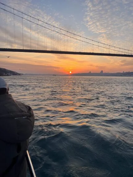 Sun setting under the Bosphorus Bridge, viewed from a yacht deck