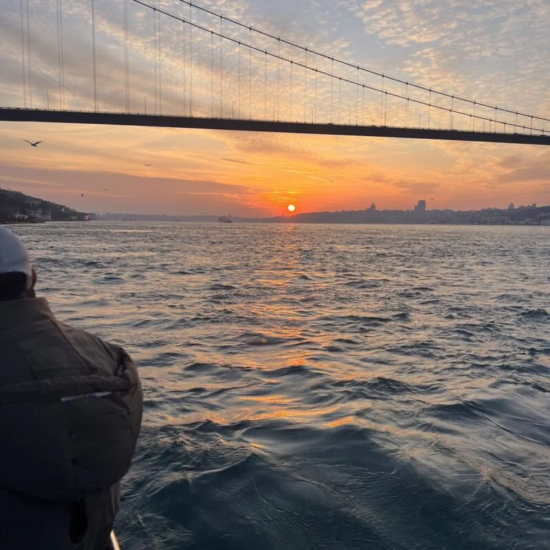 Sun setting under the Bosphorus Bridge, viewed from a yacht deck