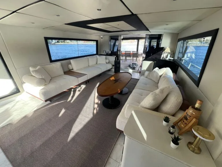 Yacht salon with panoramic windows and lounge seating, opening to the aft deck